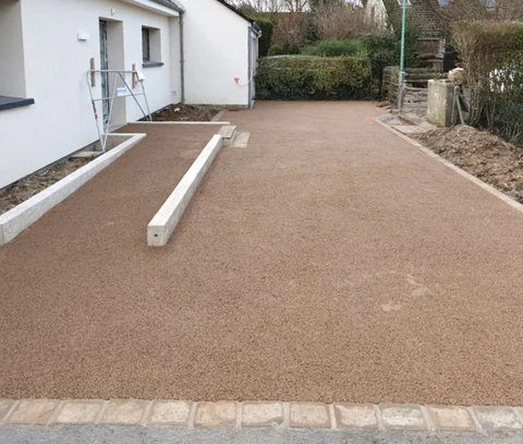 Chantier extérieur d'aménagement paysager résidentiel avec installation d'un revêtement en béton désactivé ocre