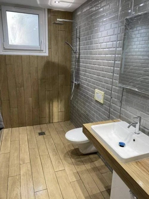 Salle de bain moderne avec douche à l'italienne, carrelage métro gris anthracite aux murs, sol imitation parquet bois