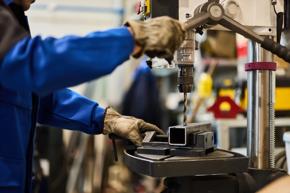 Atelier extérieur avec artisan travaillant en arrière-plan, établi en bois avec matériaux métalliques